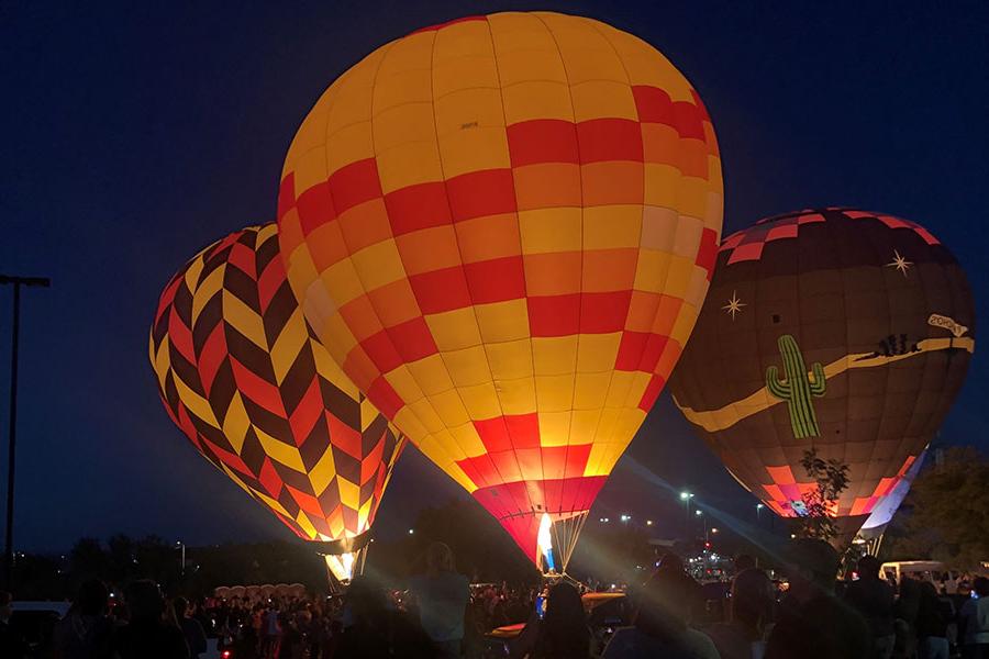 Three hot air balloon in full burn with their yellow and red tops glowing.